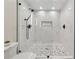 Walk-in shower with decorative stone floor, glass doors, and black shower fixtures at 280 Lakestone Pkwy, Woodstock, GA 30188