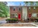 Charming brick townhome with well-manicured landscaping and vibrant red doors at 450 High Creek Trce, Roswell, GA 30076