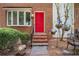Bright red front door with decorative hanging flowers is surrounded by a manicured garden at 450 High Creek Trce, Roswell, GA 30076