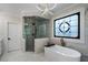 A bathroom featuring a glass shower, tub, and decorative window for natural light at 1015 Bedford Gardens Dr, Alpharetta, GA 30022