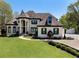 Stunning white home features manicured lawn, circular driveway, and elegant architectural details, including arched windows and stately columns at 1015 Bedford Gardens Dr, Alpharetta, GA 30022