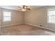 A cozy bedroom with neutral walls, a ceiling fan, two windows for natural light, and plush carpet at 2814 Brackenwood Dr, Snellville, GA 30039