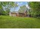 Backyard features a lush green lawn and the rear of the house surrounded by trees at 1008 Hope Springs Ct, Stone Mountain, GA 30083