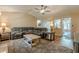 Spacious living room with hardwood floors, neutral tones, a ceiling fan, and access to other parts of the house at 5045 Edinborough Pl, Sugar Hill, GA 30518