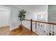 Bright upstairs hallway featuring hardwood floors, white railings, and a decorative houseplant at 4960 Shade Creek Xing, Cumming, GA 30028