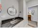 A powder room with stainless steel sink, dark granite counter and round mirror at 4960 Shade Creek Xing, Cumming, GA 30028