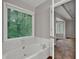 Bright bathroom features a bathtub, a window, and a large mirror at 5309 Ashley Se Dr, Conyers, GA 30094