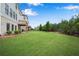 Large backyard featuring lush green grass, mature trees, and part of the back of the house at 6265 Bellmoore Park Ln, Johns Creek, GA 30097