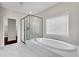 Bathroom showcasing a stylish tub and glass-enclosed shower with marble surround at 6265 Bellmoore Park Ln, Johns Creek, GA 30097