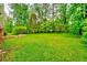 Spacious backyard with a stone patio and fire pit providing a relaxing outdoor space surrounded by mature trees and green grass at 4507 N Peachtree Rd, Dunwoody, GA 30338