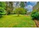 Expansive backyard with a lush lawn, stone patio, and built-in fire pit, offering a private retreat for outdoor activities at 4507 N Peachtree Rd, Dunwoody, GA 30338
