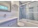 Bathroom featuring a blue-tiled shower/tub with glass door and a modern vanity with a mirror at 4507 N Peachtree Rd, Dunwoody, GA 30338