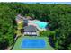 Aerial view of community pool, tennis court, and clubhouse surrounded by dense, mature trees at 4507 N Peachtree Rd, Dunwoody, GA 30338