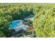 Bird's eye view highlighting a community pool, playground and tennis courts nestled amongst mature trees, promising an active lifestyle at 4507 N Peachtree Rd, Dunwoody, GA 30338