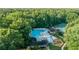 Aerial view showcasing a large community pool, clubhouse, playground and tennis courts surrounded by trees, perfect for Gathering fun at 4507 N Peachtree Rd, Dunwoody, GA 30338
