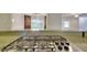 Granite kitchen island cooktop with stainless steel burners and view to living area beyond at 4507 N Peachtree Rd, Dunwoody, GA 30338