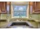 A kitchen sink under a window with wood cabinetry and a green backsplash at 4507 N Peachtree Rd, Dunwoody, GA 30338