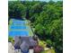 Aerial view of community tennis courts surrounded by lush greenery and building with outdoor seating at 4507 N Peachtree Rd, Dunwoody, GA 30338