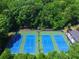 Aerial view of four pristine tennis courts surrounded by lush greenery, offering a private and scenic recreational experience at 4507 N Peachtree Rd, Dunwoody, GA 30338