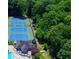 Aerial shot features tennis courts, clubhouse with tables and chairs, and verdant surroundings at 4507 N Peachtree Rd, Dunwoody, GA 30338