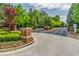 Gated community entrance with lush landscaping, brick accents, and paved road at 486 Raven Brook Ln, Suwanee, GA 30024