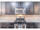 Stainless steel microwave and stovetop with dark cabinets and granite counters in a modern kitchen at 486 Raven Brook Ln, Suwanee, GA 30024