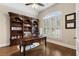 Study featuring an expansive desk and a wall of shelving, plantation shutters, and hardwood floors at 1062 Meadow Grass Ln, Powder Springs, GA 30127