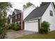 Side view of a two-car garage attached to a brick and white two-story home with green grass at 1120 Lake Lucerne Rd, Lilburn, GA 30047