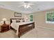 Comfortable bedroom featuring a ceiling fan, light-colored walls and carpet, and windows overlooking the greenery outside at 2253 Creekstone Ct, Marietta, GA 30062