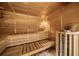 Home sauna featuring wood paneling, multi-tiered benches, and a stone heater with a protective wooden surround at 5115 Edgebrook Dr, Cumming, GA 30040
