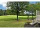 Green backyard view overlooking the golf course with mature trees and custom stone landscaping, with stair access to deck at 5309 Davenport Mnr, Cumming, GA 30041