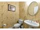 Cozy half bathroom featuring a pedestal sink, toilet, and unique golf-themed wallpaper at 5309 Davenport Mnr, Cumming, GA 30041