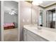 Bright bathroom featuring a large mirror over a vanity with white cabinets, as well as a doorway to an adjacent bedroom at 5309 Davenport Mnr, Cumming, GA 30041