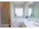 Bright bathroom featuring a soaking tub, separate shower, and a large window for natural light at 152 Cooper Creek Dr, Dallas, GA 30157