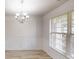 Bright dining room features elegant wainscoting, wood floors, large windows, and a modern chandelier at 881 Upland Ives Dr, Sugar Hill, GA 30518