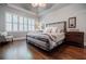 Comfortable bedroom featuring a large window, plantation shutters, a tray ceiling, and a stylish metal bed frame at 7155 Hartsfield Pl, Suwanee, GA 30024