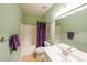 Well-lit bathroom featuring a shower with a purple curtain, toilet, and vanity with double sinks at 905 Downyshire Dr, Lawrenceville, GA 30044