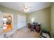 This bedroom is currently used as an office, featuring a ceiling fan and a view into the kitchen at 905 Downyshire Dr, Lawrenceville, GA 30044