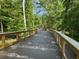 This walking path features a wooden safety fence and is surrounded by a dense forest at 378 Rhodes House Dr, Suwanee, GA 30024