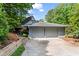 View of home with spacious two-car garage and lush greenery, set in a tranquil, wooded environment at 3863 Dundee Ne Dr, Roswell, GA 30075