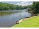 Beautiful lake view featuring a private dock with steps, grassy lawn and mature trees at 3863 Dundee Ne Dr, Roswell, GA 30075