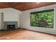 Bright living room with wood floors, fireplace, large window, and views of a serene lake and wooded landscape at 3863 Dundee Ne Dr, Roswell, GA 30075