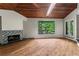 Cozy living room with hardwood floors, fireplace, skylight, and large window framing picturesque views of the water and trees at 3863 Dundee Ne Dr, Roswell, GA 30075