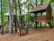 Custom treehouse featuring a climbing wall, playhouse, bridge, stairs, and wood chip ground cover at 3863 Dundee Ne Dr, Roswell, GA 30075
