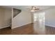 Open-concept living room with stairs, modern ceiling fan, wood-look floors, neutral paint, and lots of light at 5280 Tussahaw Xing, Mcdonough, GA 30252
