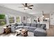 Bright living room features an oversized grey sofa, hardwood floors and access to a modern kitchen at 5751 Green Arbor Way, Sugar Hill, GA 30518