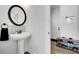 Neat powder room showcases a pedestal sink, round mirror, and a rack of shoes near the door at 5751 Green Arbor Way, Sugar Hill, GA 30518
