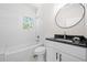Bright bathroom with a tub, white subway tile, modern fixtures, black countertops, and a single sink vanity at 2111 Holly Hill Dr, Decatur, GA 30032