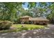 Beautiful brick home nestled among trees with a green lawn and charming curb appeal and long driveway at 5027 Castlewood Sw Dr, Lilburn, GA 30047