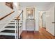 Hallway with wood floors, stairs, white trim, artwork and open doorways into other rooms at 5027 Castlewood Sw Dr, Lilburn, GA 30047